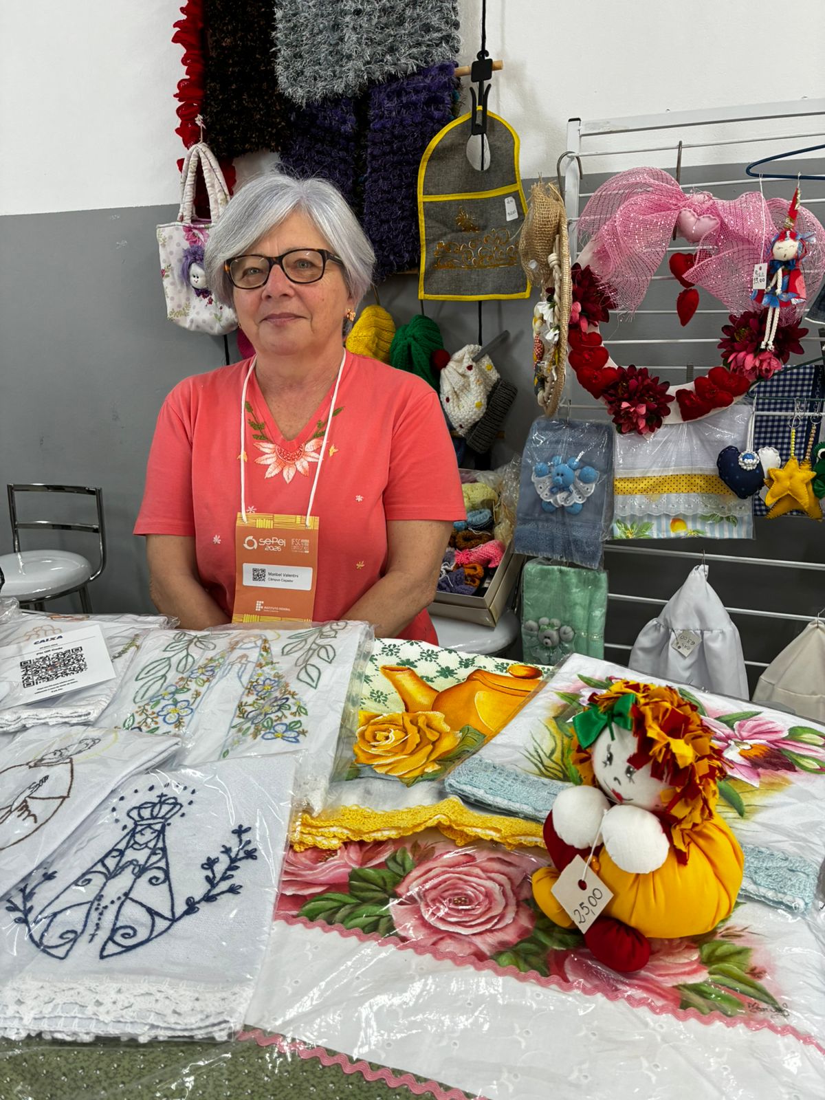Aposentada Maribel Valentini mantém um estande com bordados, crochês, tricôs e pinturas na Feira Solidária da Sepei 2026. Foto: Maykon Oliveira